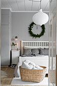 Basket at foot of white wooden bed in bedroom with grey walls