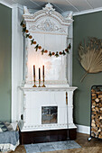 White tiled stove with candles and Christmas garland in corner of room