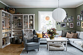 Armchair with sheepskin, coffee table, sofa and sheles in cosy living room