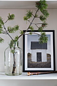 Pine branch in glass jar, picture and recorder on shelf