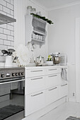 Cooker with oven, white base cabinets and plate rack on wall