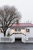 Weißes Holzhaus mit Weihnachtsdekoration im Eingangsbereich
