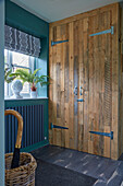 Rustic fitted cupboard in hallway with petrol-blue wall