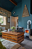 Rollbarer DIY-Couchtisch aus recyceltem Holz und Holzofen im Wohnzimmer mit petrolfarbener Wand