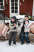 Kinder mit Marshmallow-Spießen auf verschneiter Terrasse