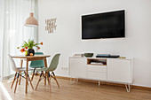 Round table and wall-mounted TV above sideboard in living room