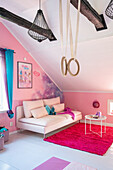 Bright upholstered sofa and gymnastic ring set in the attic room with pink wall
