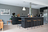 Bar stools at the kitchen island in modern open kitchen in grey