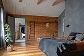 Rustikale Holzwand im Schlafzimmer in Naturtönen mit hoher Decke