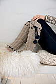 Woman wearing knitted leg warmers sitting on knitted cushion