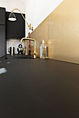 Black kitchen with gold backsplash and faucet fixtures