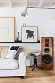 White sofa, above shelf with modern art, stool and speakers in loft flat