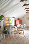 Esstisch mit Stühlen in offenem Wohnraum mit weiß gestrichener Holzdecke