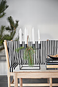 Christmas decorated candles on coffee table in front of sofa with striped overlay