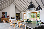 Kitchen island below pendant lights in open-plan interior with gable roof