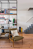 Retro armchair in open plan family living space with skateboards and open shelving unit