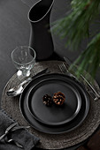 Black place setting decorated with conifer cones