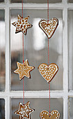 Gingerbread shapes threaded on string hung in window