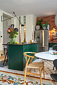 Essbereich mit Klassikerstuhl vor Küchentheke mit grüner Front