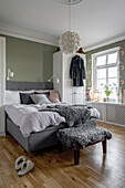 Grey double bed with animal fur, stool, and wardrobe in bedroom