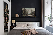 Landscape painting on black wall in a classic bedroom