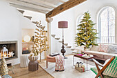 Bright living room with Christmas tree in front of arched window, staircase in background