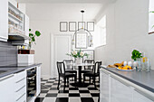 Helle Küche und kleiner Essbereich mit schwarz-weißem Fliesenboden