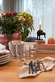 Cutlery, glasses, crockery and bouquet of flowers on dining table