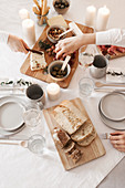 Cheeseboard and bread on table set with white tablecloth and candles