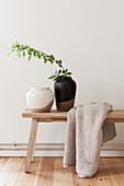 Ceramic vases and linen blanket on wooden bench