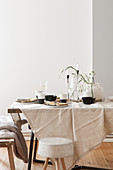 Gedeckter Tisch mit naturfarbener Tischdecke und schwarz-weißem Geschirr