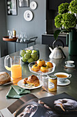 Laid breakfast table with croissant, jam, tea, fruit and juice