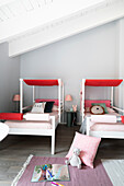 Teilweise überdachte Betten in Rosa und Rot im Geschwisterzimmer