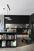 Schwarze Einbauküche, Kücheninsel mit Stauraum für Kochbücher und Servierwagen