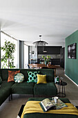 Green corner sofa with cushions and ottoman in open plan living space