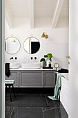 Waschtischmöbel mit zwei Aufsatzbecken, darüber runde Spiegel im Badezimmer