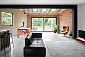 Black leather couch in open-plan interior with brick wall