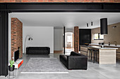 Black leather couch in open-plan interior with brick and rendered walls