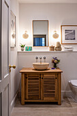 Wooden washstand with countertop basin below shelf, mirror and wall-mounted lights