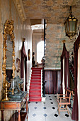 Hallway with cameo, console table, gilt-framed mirror, foil wallpaper and staircase