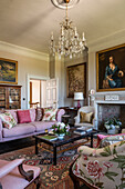 Portrait above fireplace in drawing room with pink sofa in 18th century mansion