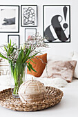 Bouquet of tulips and box on wicker tray, modern pictures on wall in the background