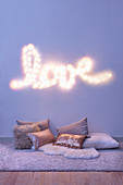 Fairy lights spelling 'LOVE' and various cushions on the floor