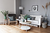 White sofa, armchair and round coffee table in grey-and-white living room
