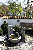 Zen-Garten mit Wasserspiel, Buchsbaum und Buddha-Köpfen im Frühling