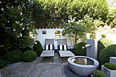 Zen garden in summer with water fountain and loungers