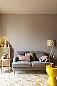 Gray upholstered sofa and floor lamp in the living room, yellow stool