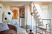 Begehbarer Kleiderschrank hinter Vorhang, weiße Treppe zum Zwischengeschoß