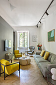 Yellow armchairs, coffee table, and gray sofa in narrow living room interior