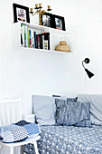 Shelves above bed with scatter cushions and bedspread in shades of blue